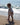White oversized t-shirt with yellow "amore" text worn by toddler on sandy beach near ocean waves.